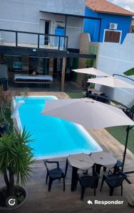 a pool with tables and umbrellas next to a building at Espaço Varanda in Sao Paulo