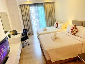 a hotel room with two beds and a flat screen tv at One Service Suites KLCC in Kuala Lumpur +16 photos