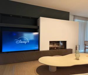 a living room with a table and a large screen tv at Biervlietmolen Vakantiewoning in Diksmuide