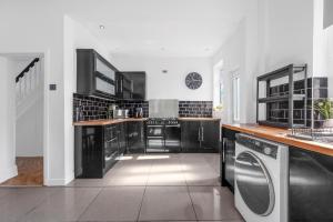 a kitchen with black cabinets and a washer and dryer at Three Bedroom House by Brookland Stays Serviced Accommodation Short Lets Manchester with Free WiFi in Manchester
