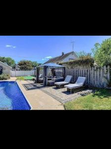 a backyard with a pool and two lounge chairs next to a fence at Jersey Oasis in Hazelton