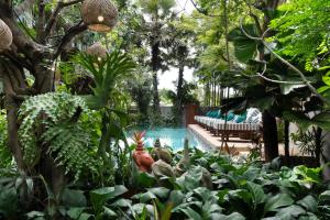 una piscina en un jardín con árboles y plantas en The Nature & Villas, en Siem Reap