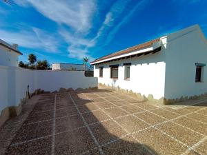 un bâtiment blanc avec une clôture et un ciel bleu dans l'établissement Casa Monte, à El Palmar 2 autres photos