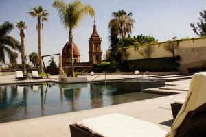 a swimming pool with a clock tower and palm trees at HS HOTSSON Hotel Leon in León