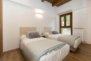 two beds in a white room with a window at Sueños del Garmo by BeValle in Panticosa