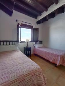 two beds in a room with a window at Casa Pueblo in El Palmar