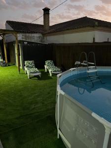 a backyard with a pool and two lounge chairs at Alojamiento Rural Coral 2 in Roche