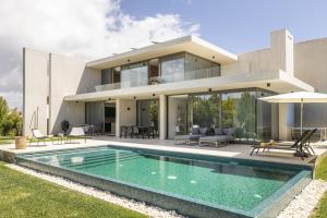 a house with a swimming pool in front of it at Troia Design Villa by CadenzaLux in Troia