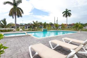 a swimming pool with two lounge chairs next to a swimming pool at Three Bedroom Villas in Drax Hall - Pool Gym - 24hr Security - Beach Closely in Saint Annʼs Bay