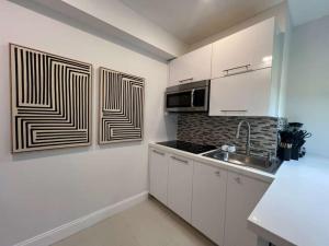 a kitchen with white cabinets and a sink at Chic Modern Studio with Queen Bed in Fort Lauderdale