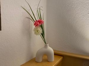 a white vase with a pink flower in it on a table at Residenz Maroi - Wasle in Sankt Anton am Arlberg
