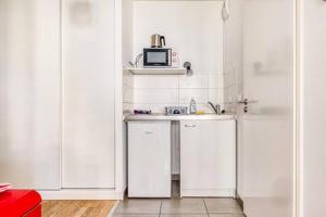 a white kitchen with a sink and a microwave at charmant appartement en plein coeur de Trouville in Trouville-sur-Mer
