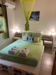 a bedroom with a green bed with towels on it at Bungalow Ludivine in Sainte-Anne