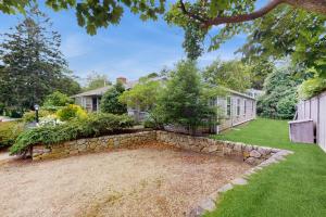 a home with a stone retaining wall and a yard at Little Cozy Corner in Edgartown