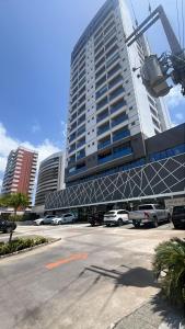 un grand bâtiment avec des voitures garées dans un parking dans l'établissement STUDIO Mar azul 1206, à São Luís