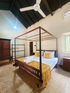 Un dormitorio con una cama con dosel de madera y almohadas amarillas. en CalmDown, en Ahangama