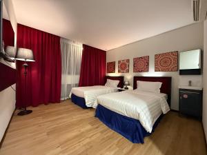 a hotel room with two beds and red curtains at City Homestay in Miri