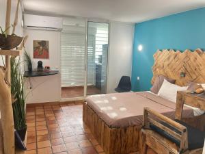 a bedroom with a wooden bed and a blue wall at Cosy Studio in La Trinité