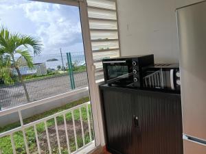 a room with a balcony with a microwave and a window at Cosy Studio in La Trinité