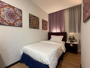 a bedroom with a bed with white sheets and paintings on the wall at City Homestay in Miri