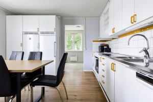 a kitchen with white cabinets and a wooden table with chairs at Bright & Spacious Getaway in Lötgärde