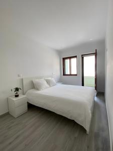 a white bedroom with a large bed and a window at T4 Furadouro with sea view in Furadouro