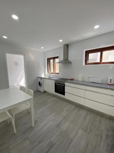 a kitchen with white cabinets and a table and a table and a table at T4 Furadouro with sea view in Furadouro