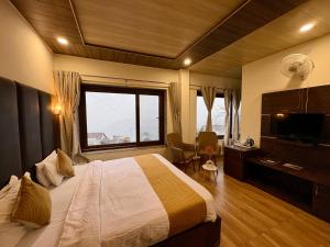 Una habitación de hotel con una cama y una ventana grande. en Hotel Jannat, en Dalhousie