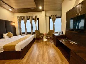 Un dormitorio con una cama, un escritorio y un televisor. en Hotel Jannat, en Dalhousie
