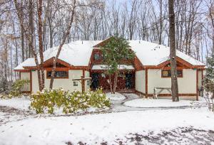 a house covered in snow in the woods at Ski-In 5BR Retreat at Boyne Mtn - Walk to Lifts & Fun! in Boyne Falls