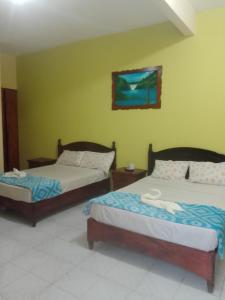 ein Schlafzimmer mit zwei Betten und einem Gemälde an der Wand in der Unterkunft Hotel Posada Real in Chiapa de Corzo