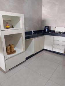 アパレシダ・デ・ゴイアニアにあるCasa Borgesの白いキャビネットと黒いカウンタートップを備えたキッチン +2枚の写真