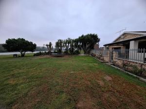 a large yard with trees and a house and a fence at Addo River Den 4 in Gqeberha