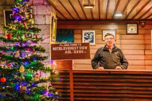 un homme assis sur un banc à côté d'un arbre de Noël dans l'établissement Hotel Everest View, à Khumjung