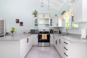 a kitchen with white cabinets and a black appliance at Three Bedroom Villas in Drax Hall - Pool Gym - 24hr Security - Beach Closely in Saint Annʼs Bay