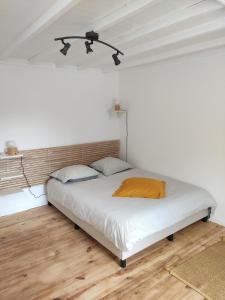 a bed in a white room with a wooden floor at Chez madame Hulotte in Saint-Nazaire