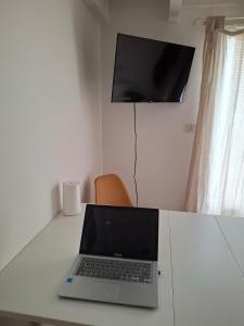 a laptop computer sitting on a white desk with a television at Chez madame Hulotte in Saint-Nazaire
