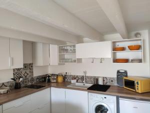 a white kitchen with a sink and a microwave at Chez madame Hulotte in Saint-Nazaire +10 photos