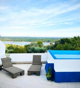 two chairs on a patio with a view of a river at Casa Lusa Montargil in Montargil