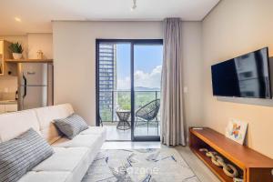 a living room with a couch and a television at Sua estadia exclusiva a poucos passos do Mar em Meia Praia - FFS in Perequê