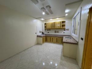 a large kitchen with white walls and wooden cabinets at Appartement 135m new and furnished very good looking in Oujda +4 photos