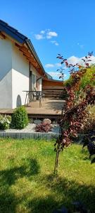 a house with a wooden deck with a chair on it at Apartamenty Modrzewiowe Tarasy in Chojnice