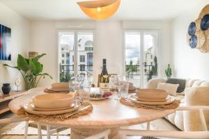 ein Esszimmer mit einem Tisch mit Gläsern und Weinflaschen in der Unterkunft Appartement F3 Neuf Vue sur la Seine avec Parking Gratuit Proche Paris Tour Eiffel & Disney in Cormeilles-en-Parisis