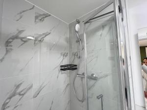 a shower in a bathroom with white marble at Little studio flat in Southgate