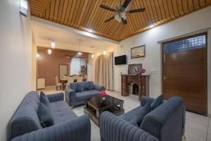 uma sala de estar com sofás azuis e uma ventoinha de tecto em The Corner House I Pet friendly & Serviced Villa I Open Air Lawn & Plunge Pool I Bonfire I Dance I Music I Full Party I Kasauli By Exotic Stays em Kasauli mais 18 fotografias
