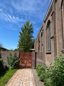 a brick building with a red gate and a brick walkway at De Hoffstee in Minnertsga +33 photos