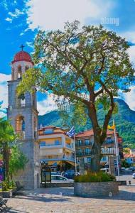 a tree in front of a building with a tower at HOME OF OLYMPOS STUDIO in Litochoro