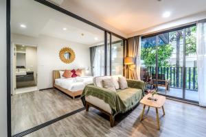 a bedroom with a bed and a couch at Elegant 1BR Garden-View Condo - The Deck Patong in Patong Beach
