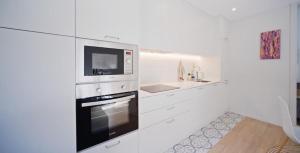 ブラガにあるRaio 33 - Apartamento Centro Histórico Bragaの白いキッチン(コンロ、電子レンジ付)