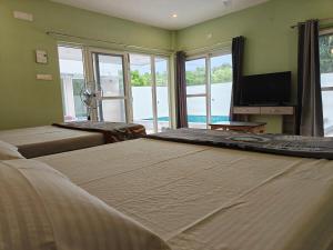 a large bedroom with two beds and a television at Maple Dreams Retreat- A Pool side Villa in Pondicherry